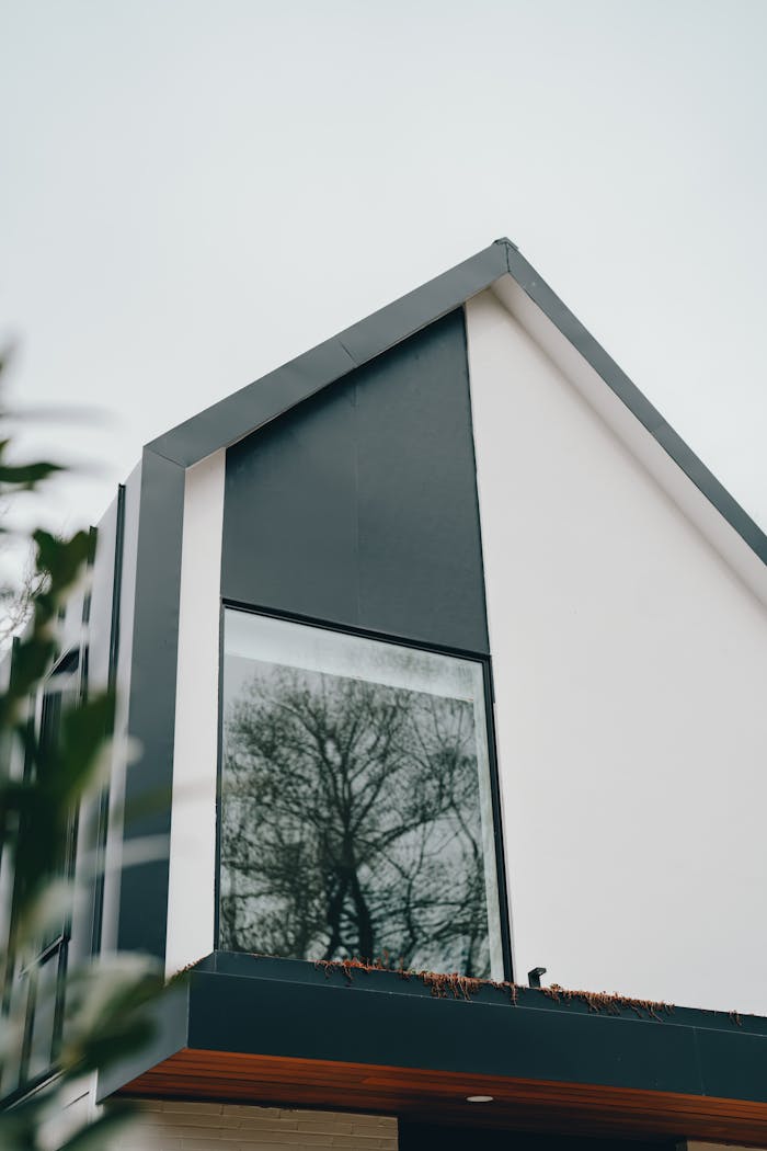 Contemporary house design featuring a large reflective window with a sleek facade.