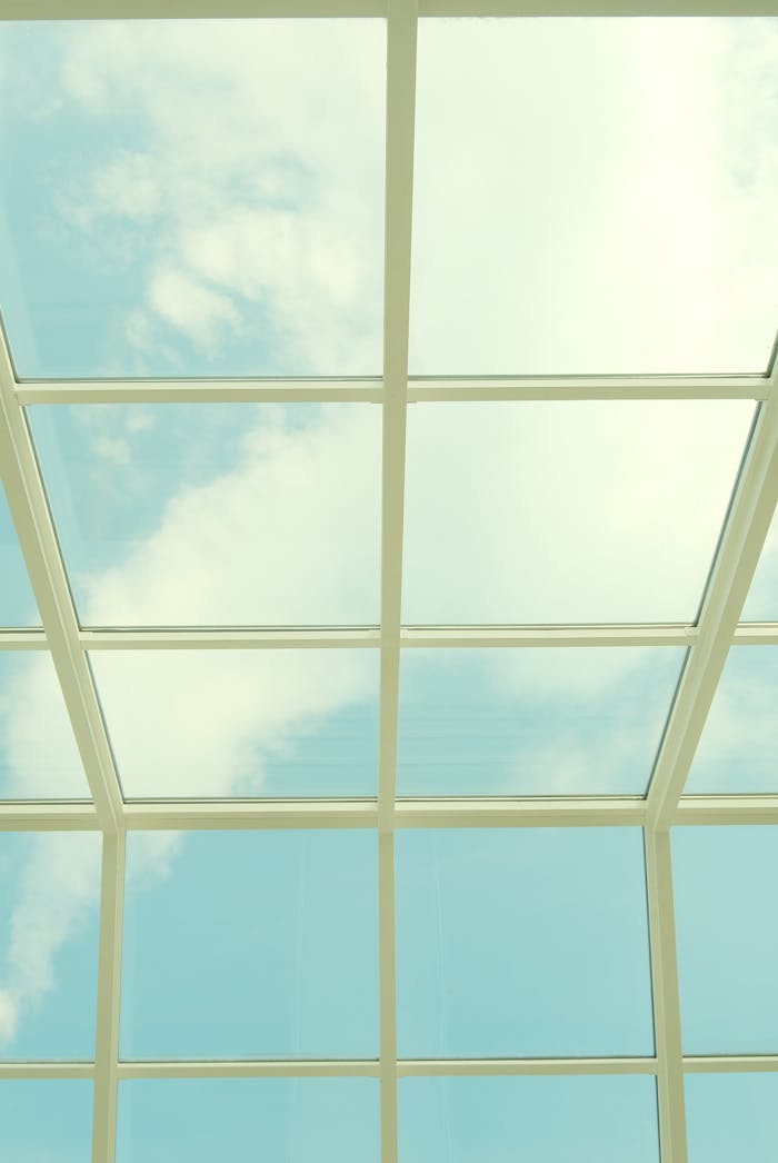 About A serene view of clouds through a geometric glass skylight.